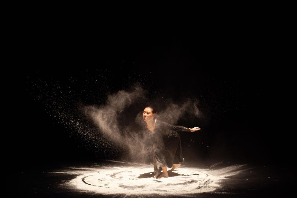 一名舞者在舞台上表演，在沙子中旋转，创造出独特的视觉效果.